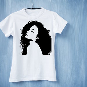 May include: White t-shirt with a black silhouette of a woman with curly hair.