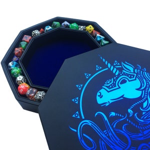 May include: A black octagonal dice tray with a blue velvet interior and a blue unicorn design on the lid. The tray is filled with colorful dice.