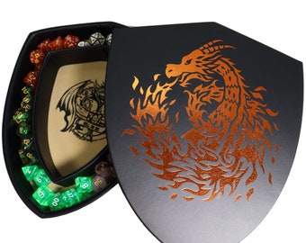 May include: A black shield-shaped box with a copper-colored dragon design. The box is open to reveal a dice tray with green dice and a brown felt interior. The box has the text "Roll One Die" printed on the inside.