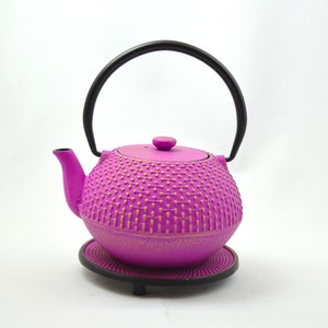 Könnte beinhalten: Eine violette gusseiserne Teekanne mit schwarzem Henkel und goldfarbenem, gesprenkeltem Design. Die Teekanne steht auf einem schwarzen Metallständer.