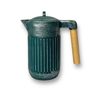 Może przedstawiać: Zielony ceramiczny dzbanek do kawy z drewnianym uchwytem. Dzbanek ma fakturowaną powierzchnię i pionowe linie.