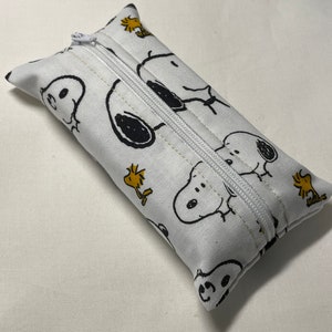 Pu&ograve; includere: Porta fazzoletti bianco con cerniera e un motivo ripetuto di personaggi Snoopy e Woodstock in bianco e nero.