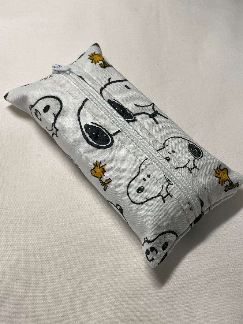 Pu&ograve; includere: Porta fazzoletti bianco con cerniera e un motivo ripetuto di personaggi Snoopy e Woodstock in bianco e nero.