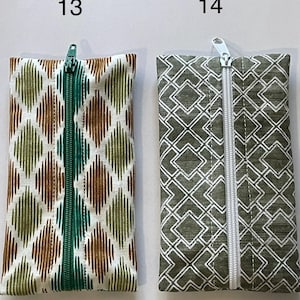 May include: Two rectangular zipped pouches labelled 13 and 14. Pouch 13 features a white fabric with a green and brown diamond ikat pattern and a green zip. Pouch 14 features a dark green fabric with a white geometric square pattern and a white zip.