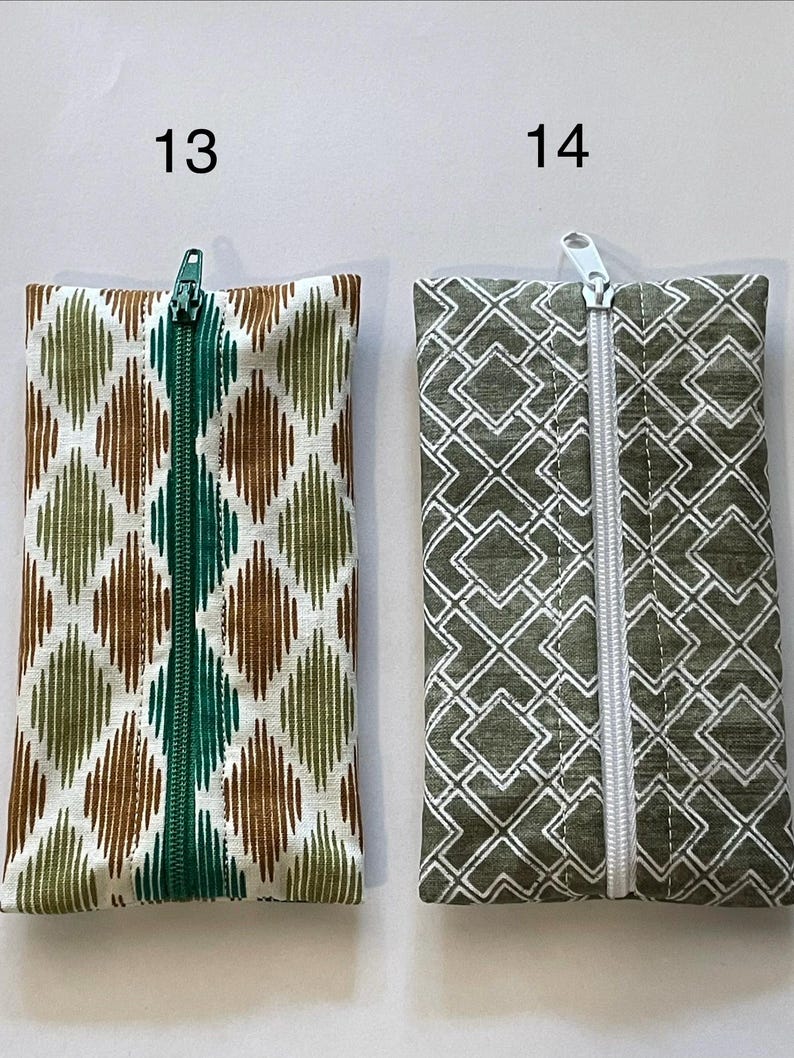 May include: Two rectangular zipped pouches labelled 13 and 14. Pouch 13 features a white fabric with a green and brown diamond ikat pattern and a green zip. Pouch 14 features a dark green fabric with a white geometric square pattern and a white zip.