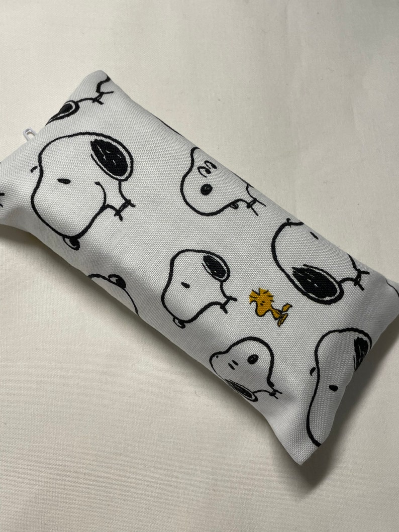 Pu&ograve; includere: Copertura per scatola di fazzoletti in tessuto bianco con un motivo ripetitivo in bianco e nero di Snoopy e Woodstock.