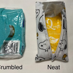 Pu&ograve; includere: Due immagini di scatole di fazzoletti, una accartocciata e l'altra riposta ordinatamente in una pochette bianca con cerniera con una stampa di un cane di cartone animato in bianco e nero. La pochette riporta il testo "Qsoft Soft & Silky Pocket Tissue 4PLY".