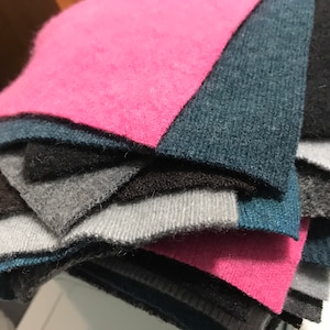 May include: A stack of fabric swatches in various shades of pink, gray, and blue. The swatches are folded and layered on top of each other.