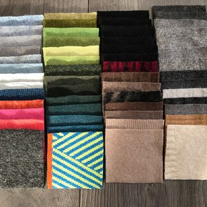 May include: A collection of fabric swatches in various colors and textures, including green, brown, blue, gray, and beige. The swatches are arranged in rows and columns, and some have a subtle pattern.