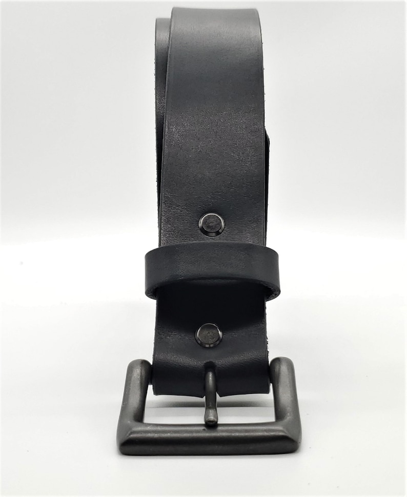 May include: A black leather belt with a gunmetal buckle. The belt is made of thick, durable leather and features a classic design. The buckle is square and has a matte finish.