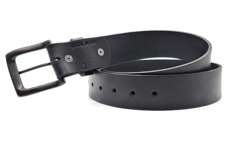 May include: Black leather belt with a gunmetal buckle. The belt is marked "MADE IN USA" and size 36. The belt has several holes for adjustment.