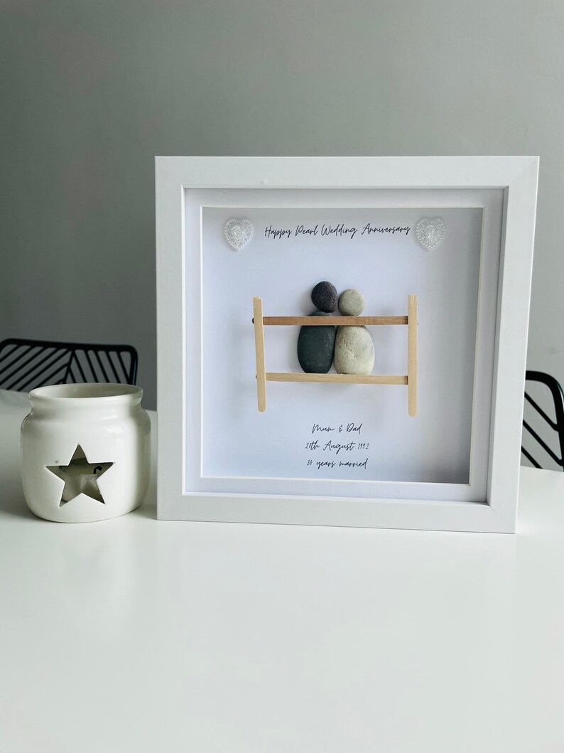 May include: White framed picture with a pebble art design of a couple on a bench. The text reads "Happy Pearl Wedding Anniversary", "Mum & Dad", "26th August 1992", and "30 years married".