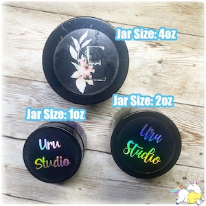 May include: Three black jars with labels. The jars are labeled with the text "Uru Studio" and the size of the jar in ounces. The jars are 1 ounce, 2 ounces, and 4 ounces.