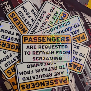 May include: A collection of rectangular stickers with a white background and black text. The stickers have a yellow border and holographic accents. The text on the stickers reads "PASSENGERS ARE REQUESTED TO REFRAIN FROM SCREAMING."