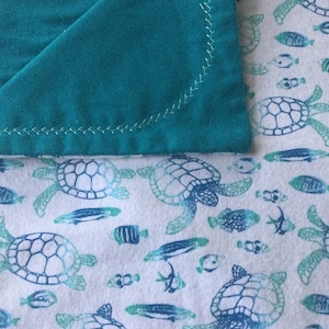 Sea Life - soft blue and aquas make this a soft ocean themed flannel baby blanket.  Turtles, fish and friends.  Ships free
