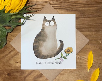 Può includere: Un biglietto bianco con un'illustrazione di un gatto grigio con occhi grandi e un girasole. Il testo sul biglietto dice "Grazie per aver aiutato miagolio!"