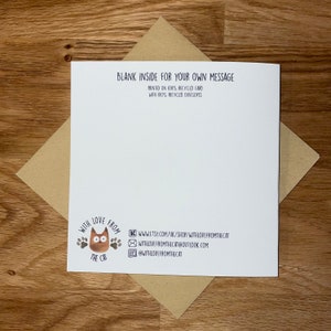 May include: A blank greeting card with a brown cat illustration and the text "With Love From The Cat." The card is printed on 100% recycled card and comes with a 100% recycled envelope. The card is on a wooden surface.