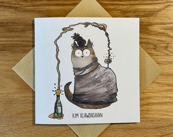 May include: A watercolour illustration of a cat wearing a black dress, a pearl necklace, and a hat. The cat is holding a glass of champagne. The cat is surrounded by a yellow and orange watercolour design that looks like a champagne bottle popping. The text "KIM KLAWDASHIAN" is written below the cat.