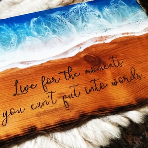 May include: Wooden serving tray with a blue and white epoxy resin ocean wave design. The tray has a quote engraved on the wood: "Live for the moments you can't put into words."