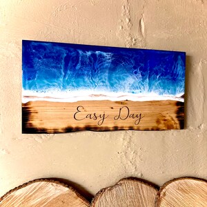 May include: A wooden sign with a blue and white resin ocean scene and the text "Easy Day" burned into the wood.