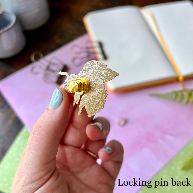 May include: Gold-toned metal pin with a locking pin back. The pin is shaped like a butterfly.