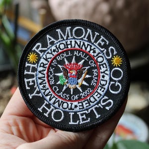 May include: A white ceramic mug with a black handle and the text "But First, Coffee" in a bold, black font. The mug is set against a blurred background, suggesting a cozy setting.