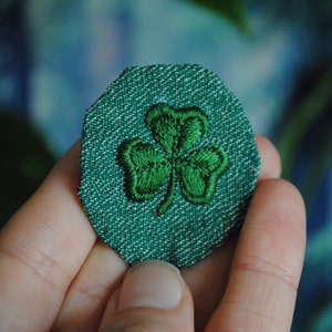 May include: A green fabric patch with an embroidered shamrock design.