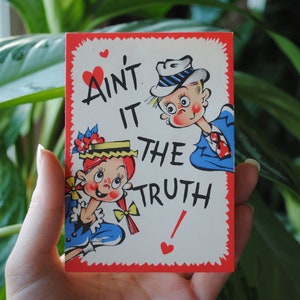 May include: A vintage Valentine's Day card with a red border and white background. The card features a cartoon couple with the text "Ain't it the truth!"