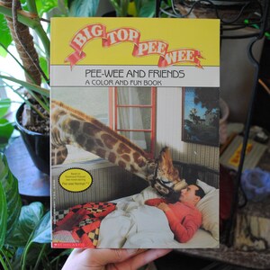 May include: A yellow and red book titled "Big Top Pee-Wee: Pee-Wee and Friends, A Color and Fun Book" with a picture of a giraffe and a man on the cover.