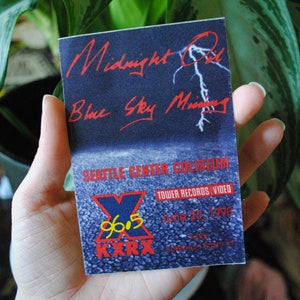 May include: A blue and red concert ticket for Midnight Oil and Blue Sky Mining at the Seattle Center Coliseum on June 25, 1996. The ticket is for a show hosted by 96.5 KXXR and Tower Records.