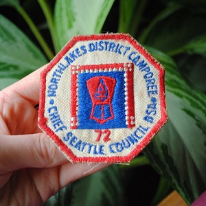 May include: A white, red, and blue embroidered patch with the text "North Lakes District Camporee - Chief Seattle Council 72".