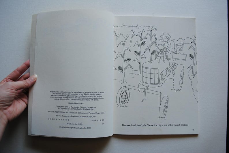 May include: A black and white illustration of a tractor driving through a field of corn. The tractor has a driver and a pig in the back. The text "Phe-wee has lots of pals. Vince the pig is one of his closest friends." is at the bottom of the page.