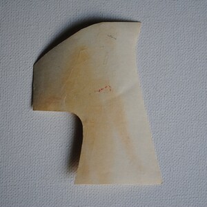 May include: A light brown paper shape resembling the number one. The shape is cut out and has a rough, textured surface.