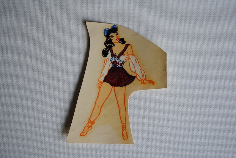 May include: A vintage illustration of a woman wearing a white and red dress with a floral pattern. She has dark hair and is wearing blue bows in her hair. The illustration is on a light brown background.
