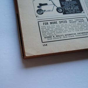 May include: A black and white magazine page with a black and white photo of a mini motorbike. The page has text that reads "FOR MORE SPEED GET HOTTER SPARK BOOK" and includes instructions on how to increase spark intensity, change over a distributor, and how to time and power. The text also includes the name and address of the company, "GEORGE R. WILLY'S AUTOMOTIVE ENTERPRISES, 2410 122nd St., Blue Island, Illinois 60406".