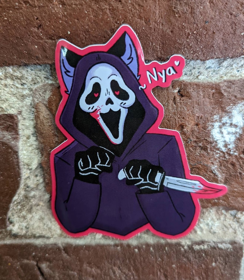 May include: A sticker of a purple and black cartoon ghost with cat ears, holding a bloody knife. The ghost has a white mask with a wide smile and red eyes. The sticker has a pink border and the text "Nyaa" written in pink.