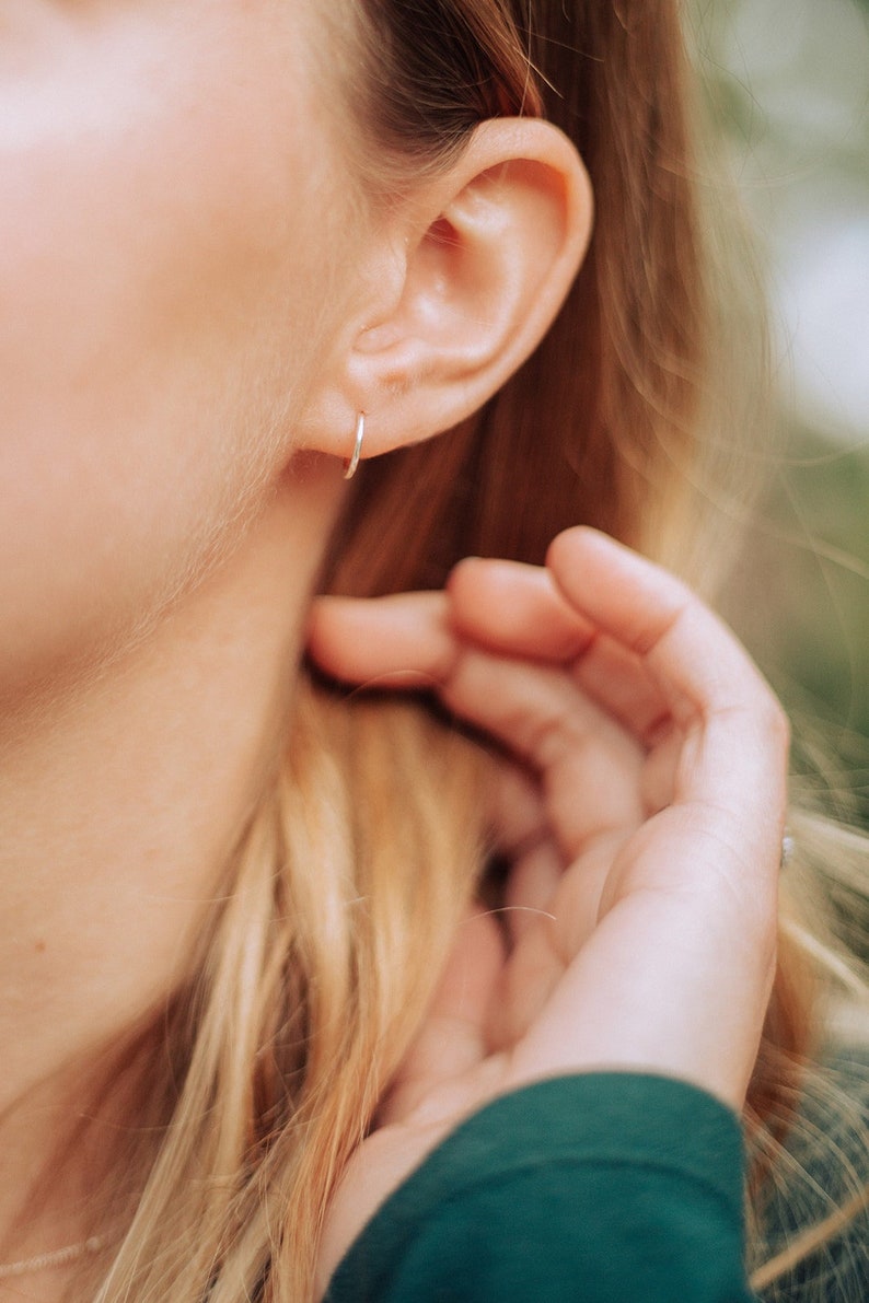 model wearing single huggie hoop earring in sterling silver