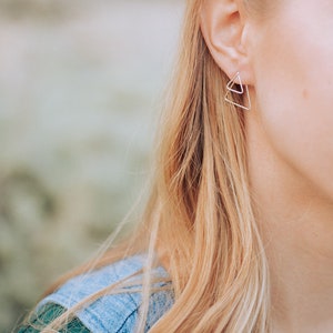 K&ouml;nnte beinhalten: Eine Frau mit langen blonden Haaren tr&auml;gt silberne Dreiecksohrringe.