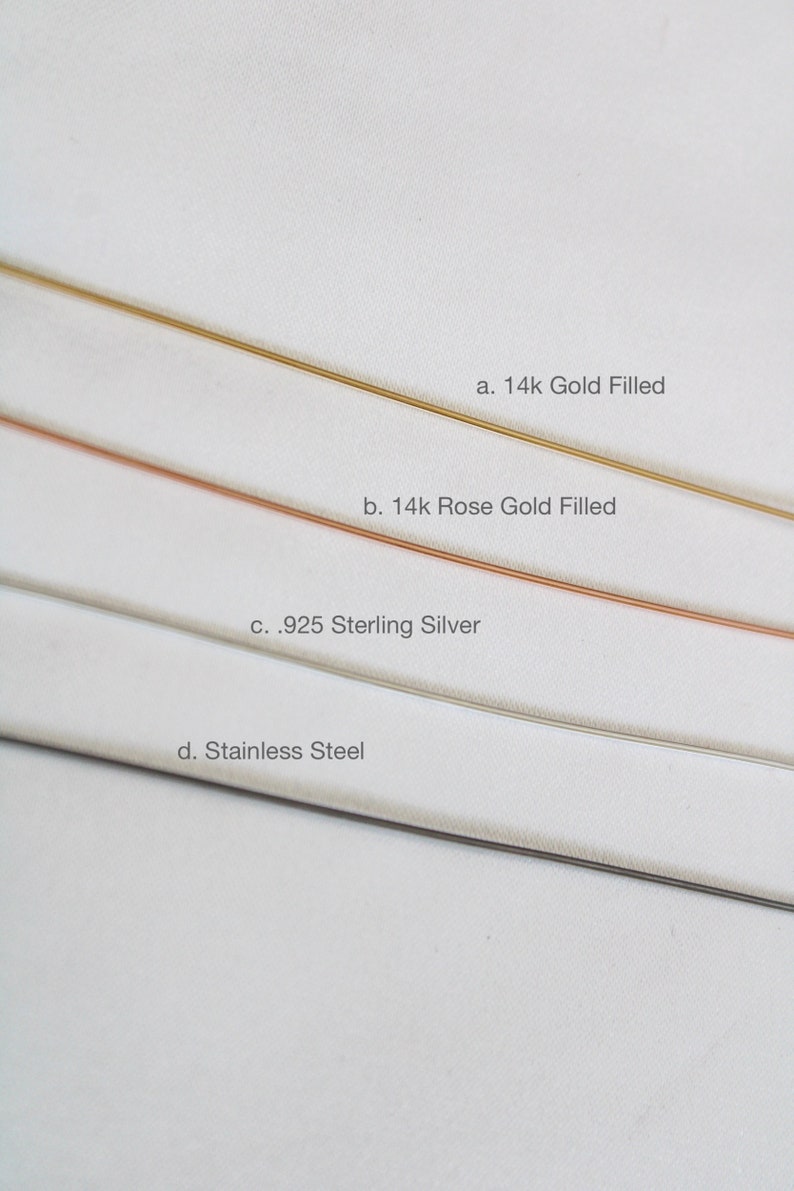 K&ouml;nnte beinhalten: Vier verschiedene Metallstreifen auf wei&szlig;em Hintergrund. Die Streifen sind mit ihrem Metalltyp beschriftet: 14k Gold Filled, 14k Rose Gold Filled, .925 Sterling Silver und Edelstahl.