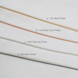 May include: Four different metal strips on a white background. The strips are labeled with their metal type: 14k Gold Filled, 14k Rose Gold Filled, .925 Sterling Silver, and Stainless Steel.