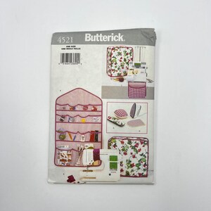 May include: Butterick sewing pattern 4521 for home organization accessories. The envelope displays illustrations of a wall-hanging organizer with red stripes, a floral sewing machine cover, a matching floral storage case, and various small sewing notions.