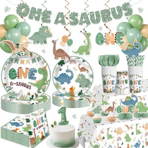 May include: A dinosaur-themed party supply set featuring green and blue balloons, a glittery 'ONE A-SAURUS' banner, paper plates, cups, napkins, and a cake topper shaped like the number one, all decorated with various dinosaur illustrations.