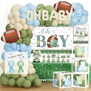 May include: A baby shower decoration set with a football theme. Includes a balloon arch with "OH BABY" and "TOUCH DOWN" balloons, a banner that says "Oh BOY", and decorative boxes with letters.