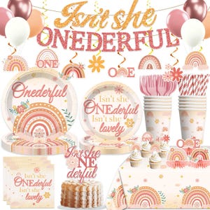 May include: A party decoration set with a "Isn't she ONEDERFUL" theme. Includes plates, cups, napkins, a cake topper, and a tablecloth, all decorated with rainbows and floral designs in shades of pink, peach, and gold. Balloons and hanging decorations complete the festive look.