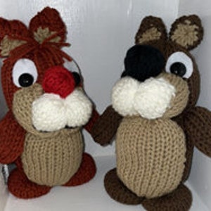 May include: Two knitted plush toys, one brown and one red, with large eyes and smiling faces. The toys are holding hands.