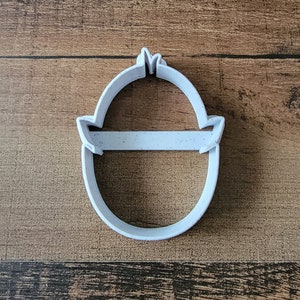 May include: White plastic cookie cutter shaped like a cartoon chick with a small beak and a round body.