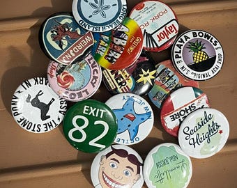 Peut inclure: Un ensemble de badges ronds et colorés avec divers motifs et textes. Les badges présentent des images d'une étoile de mer, d'un visage souriant et des textes tels que "Seaside Heights" et "Exit 82".