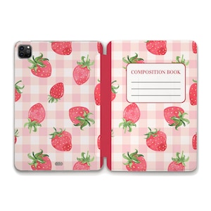 Puede incluir: Una cubierta de cuaderno de patrón vichy rosa y blanco con una encuadernación roja. La cubierta está decorada con un patrón repetido de fresas rojas. La portada tiene el texto "COMPOSITION BOOK" impreso en negro.
