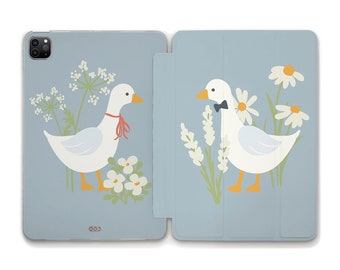 Puede incluir: Una funda de teléfono azul y blanca con un diseño de dos gansos blancos con flores. Un ganso lleva un lazo rojo y el otro lleva una pajarita negra.