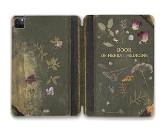 May include: A green book with a worn leather cover and dried flowers pressed into the pages. The title on the cover reads "Book of Herbal Medicine".